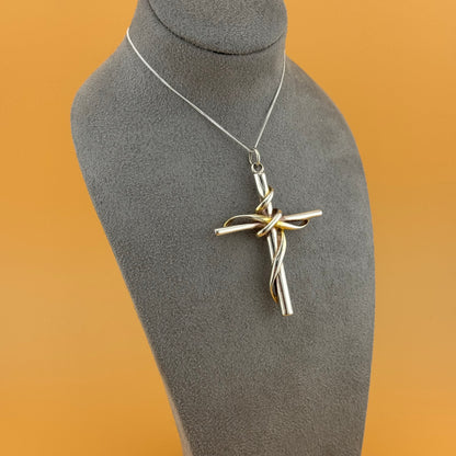 Silver cross pendant on a gray mannequin bust with a brown background