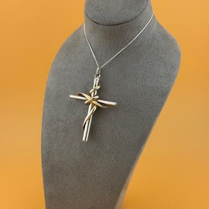 Silver cross pendant on a gray mannequin bust with an orange background