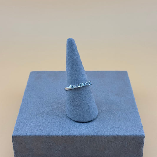 Silver ring on a blue cone-shaped stand against a beige background