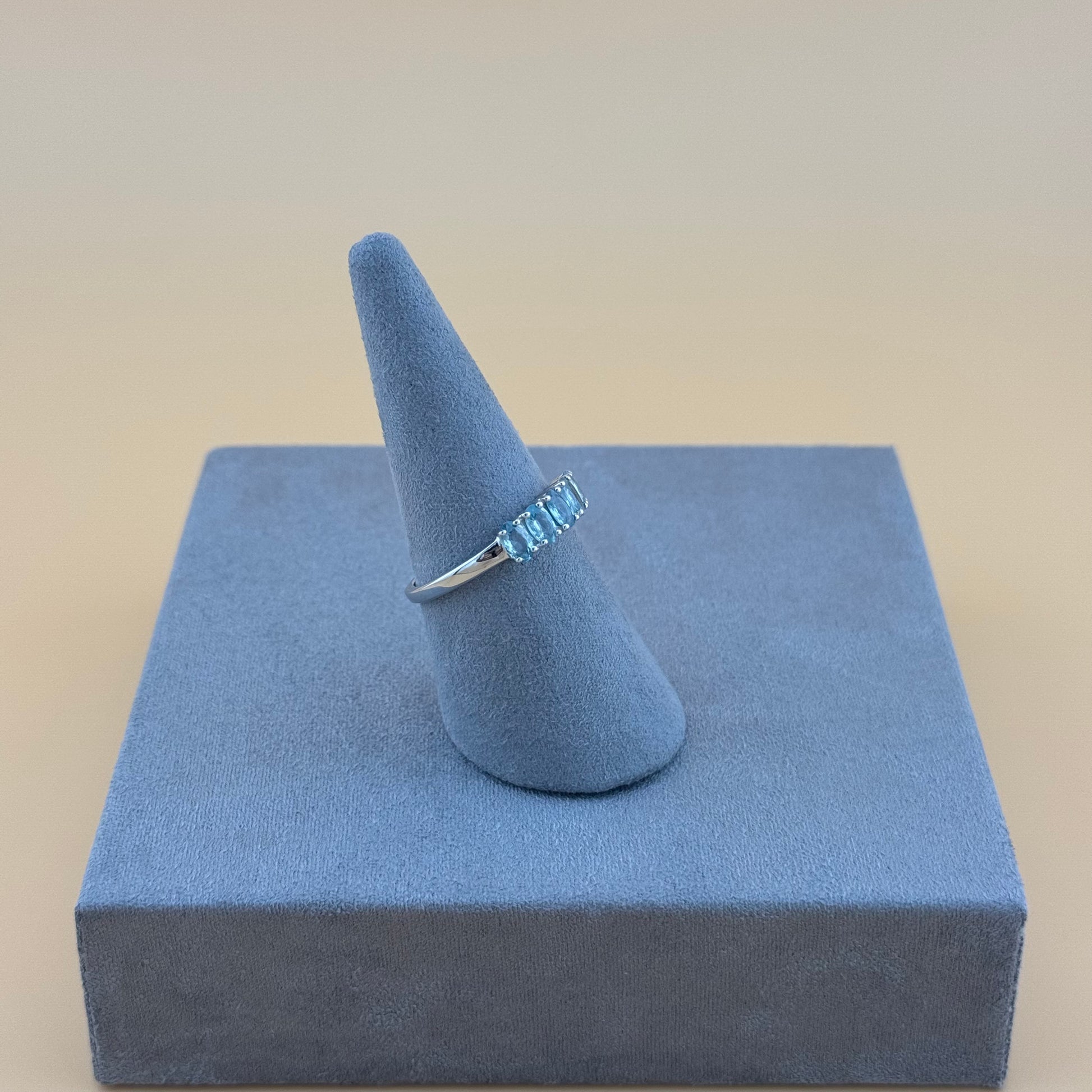 Silver aquamarine ring on a blue ring stand with a beige background