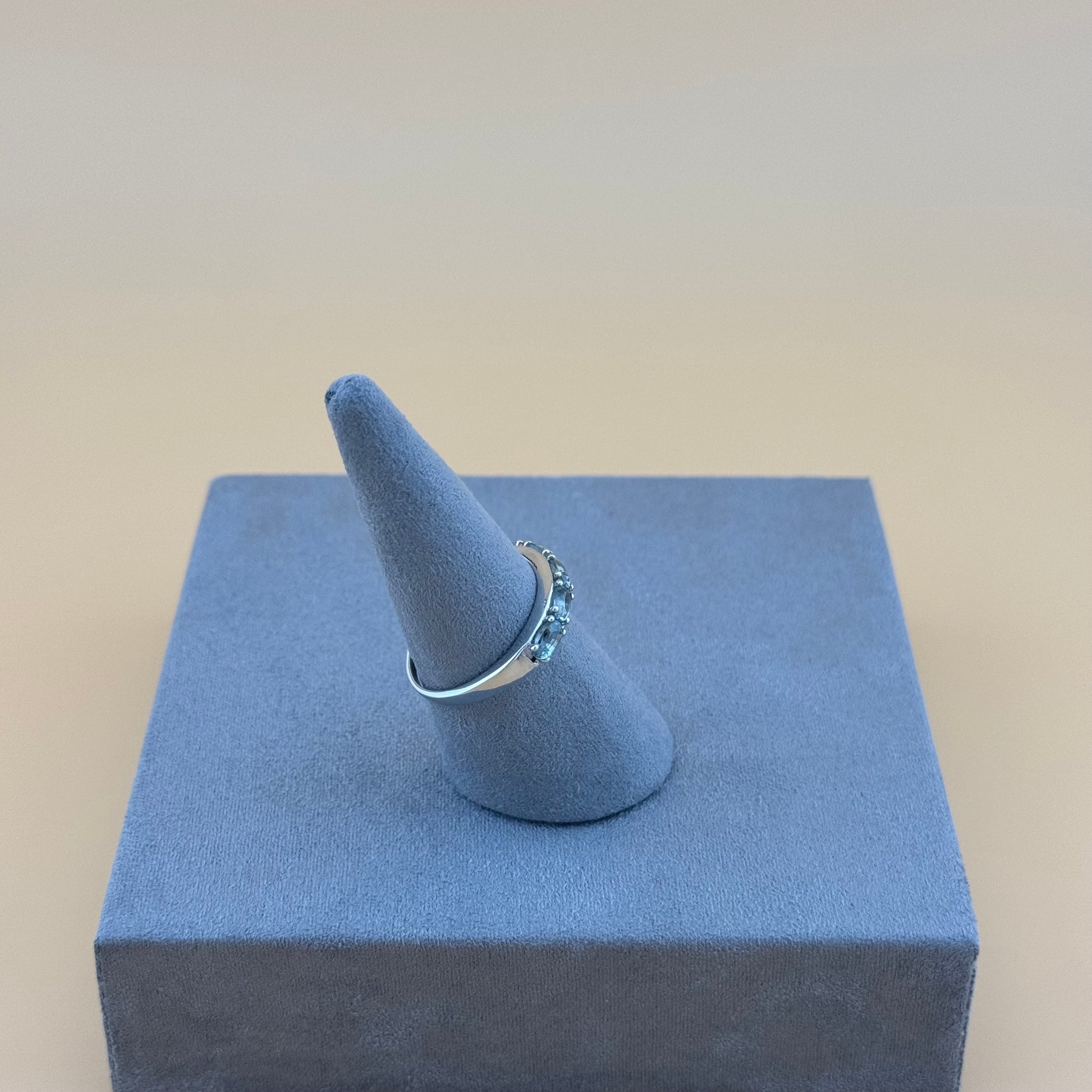 Ring on a blue cone-shaped stand with a beige background
