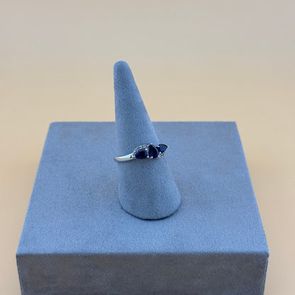 Silver ring with blue tanzanite stones on a blue stand against a beige background