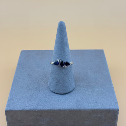 Silver tanzanite ring with a blue gemstone on a blue stand against a beige background
